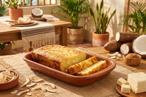 Enyucado de Coco y Queso en Barranquilla. Postre de yuca horneada con coco y queso, con bordes dorados, en un plato de barro.